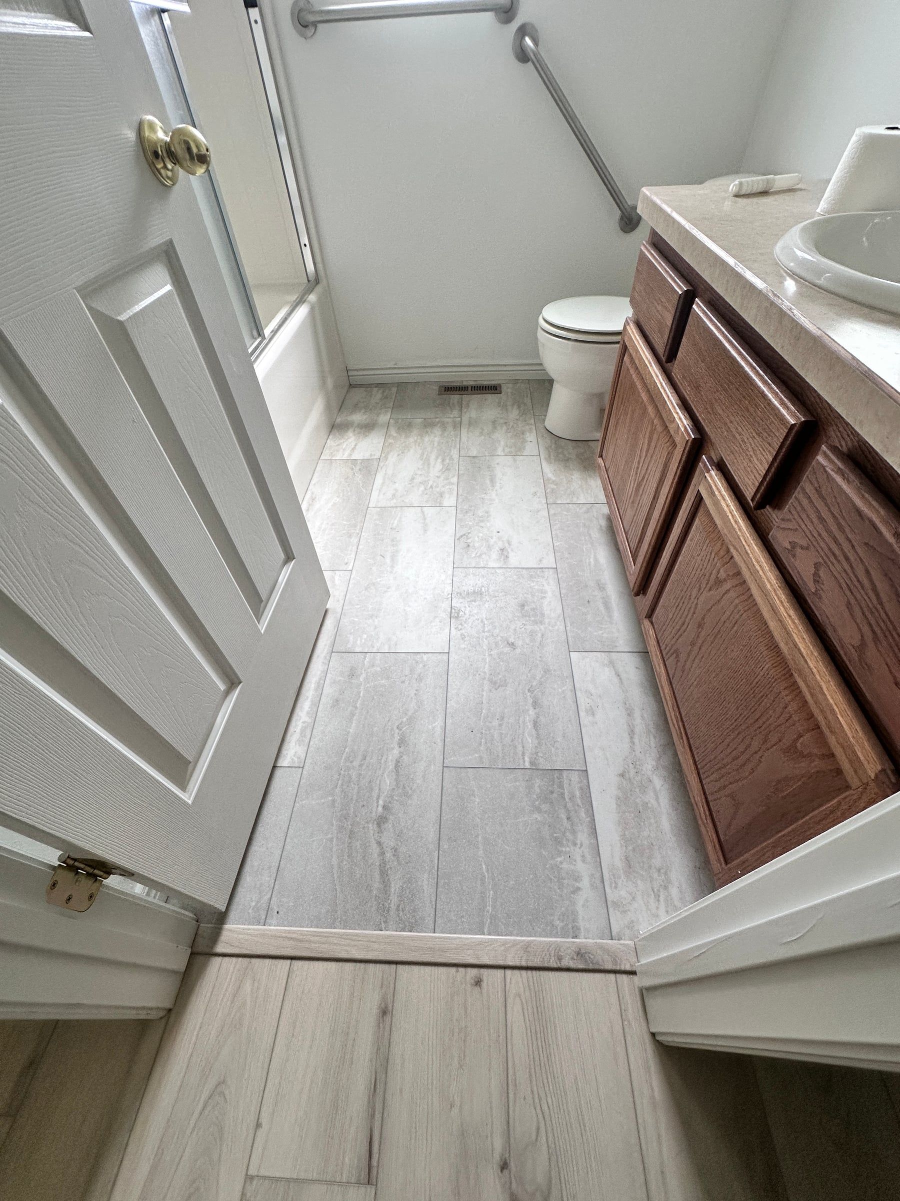 Gray tile-look luxury vinyl tile in a bathroom with wood vanity
