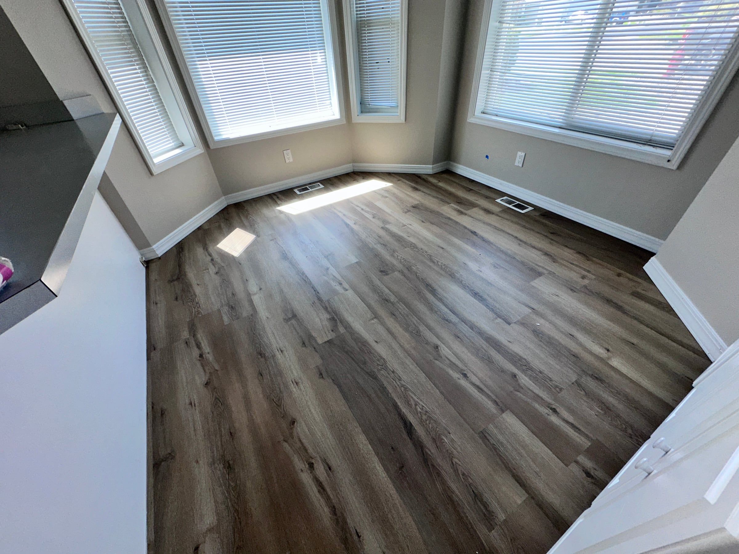 Dark luxury vinyl plank in a sunlit breakfast nook with bay windows