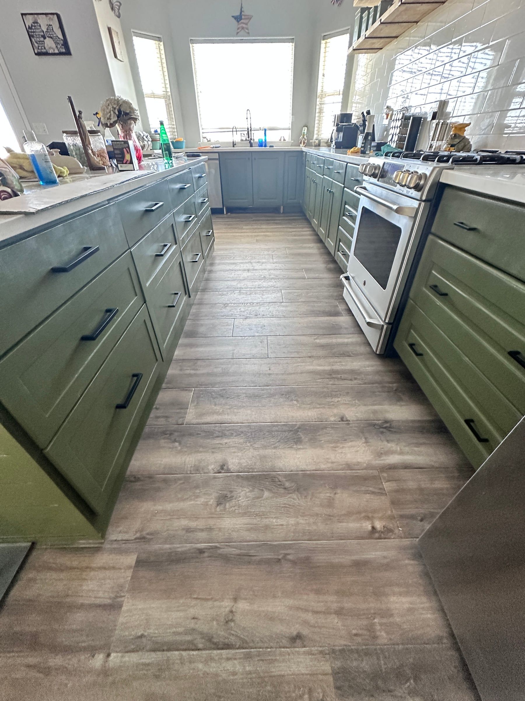 Luxury vinyl plank flooring installed in a kitchen with green cabinets