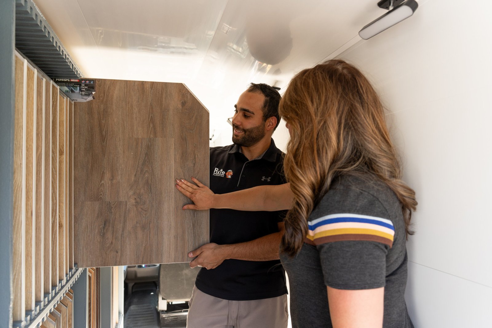 Flooring Specialist and Client Flooring specialist showing hardwood flooring samples to a client inside of a mobile flooring showroom.