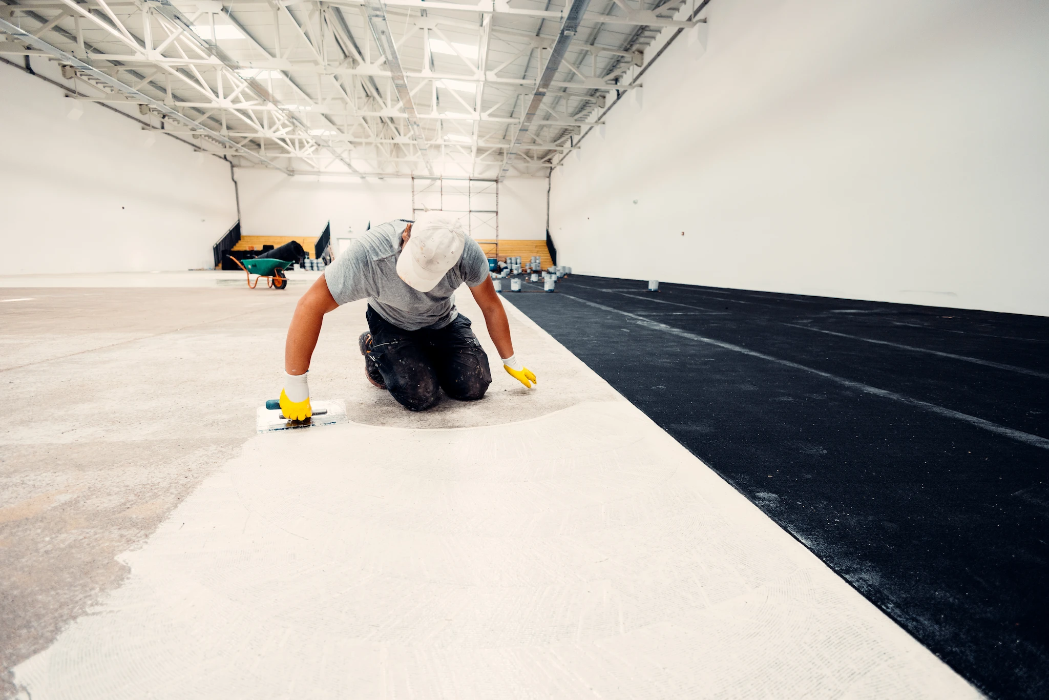 Flooring contractor installing glue-down flooring in a massive open commercial space or warehouse.